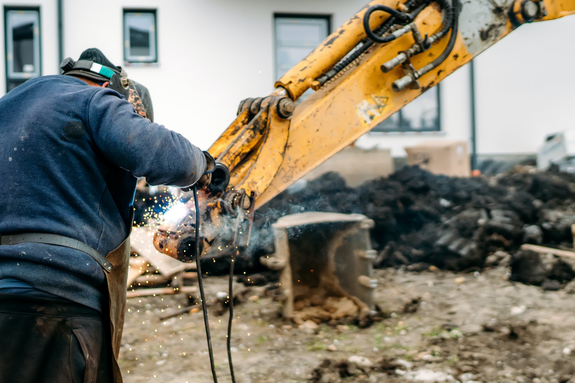 Construction worker, laborer, welding excavator arm with arc welding machinery